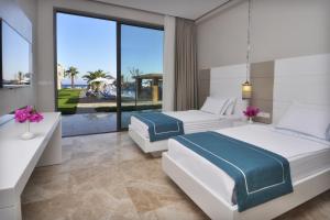 two beds in a bedroom with a view of the ocean at Lugga Boutique Hotel & Beach in Ortakent