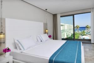 a white bedroom with a large bed and a view of the ocean at Lugga Boutique Hotel & Beach in Ortakent