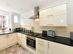 uma cozinha com armários brancos e um balcão preto em Westgate House em Cardiff