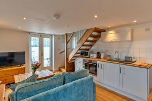 a kitchen and a living room with a blue couch at Finest Retreats - Salvay in Porthleven