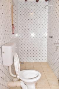 baño con aseo blanco con la tapa hacia arriba en Private room in a villa en Diani Beach