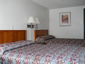 a hotel room with a bed and a chair at Value Inn Motel - Milwaukee Airport South in Oak Creek