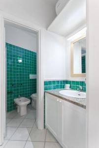 a bathroom with a sink and a toilet and green tiles at Calarossa Bay in Isola Rossa
