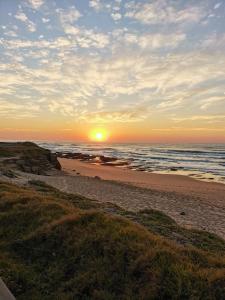 um pôr-do-sol numa praia com o oceano e o horizonte em Ocean Park Guest House em Umkomaas
