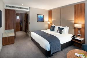um quarto de hotel com uma cama grande e uma mesa em Crowne Plaza London Heathrow T4, an IHG Hotel em Hillingdon