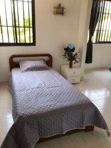 a bedroom with a bed and a vase of flowers at Habitaciones independientes cerca al aeropuerto 1 in Cartagena de Indias