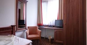 ein Hotelzimmer mit einem Schreibtisch mit einem Computer und einem Stuhl in der Unterkunft Garni-Hotel Kranich in Potsdam