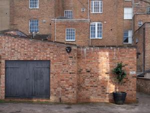 a brick building with two garage doors and a tree at Pass the Keys Montpellier mews home with parking and garden in Cheltenham