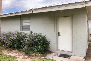 una casa bianca con una porta bianca e fiori viola di Sunnyside Studio a Panama City Beach