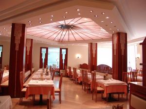 uma sala de jantar com mesas e cadeiras e um tecto grande em Hotel Excelsior em Cervia