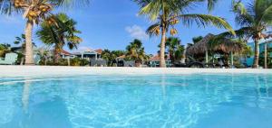 a swimming pool in front of a resort with palm trees at Waterfront apartment Palma in Kralendijk