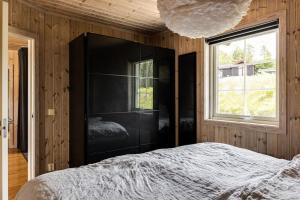 a bedroom with a black cabinet and a bed at Nice house near golf and skiing in Hestra