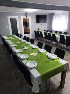 een lange tafel in een kamer met zwarte stoelen en witte borden bij Kušaona Šokac in Trenkovo