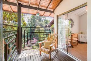 a room with a balcony with a chair and sliding glass doors at Pousada Alto de Monte Verde in Monte Verde