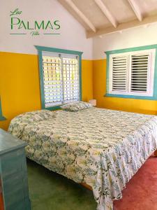 a bedroom with a bed with yellow walls and windows at Villa Las Palmas in Las Galeras