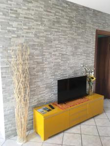 uma televisão num armário amarelo em frente a uma parede de tijolos em Appartamento Elena em Garda