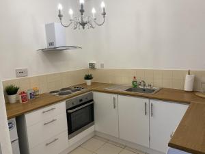 a kitchen with white cabinets and a sink and a chandelier at Inviting 1-Bed Apartment in Merchant City in Glasgow