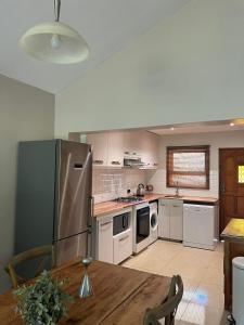 a kitchen with a stainless steel refrigerator and a table at Forest View Cottage in Pietermaritzburg