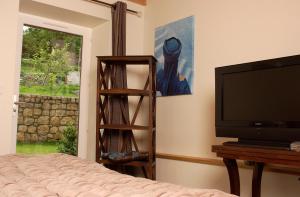 Schlafzimmer mit einem Bett, einem TV und einem Fenster in der Unterkunft Maison de famille in Camboulit