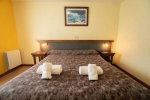 a bedroom with a bed with two towels on it at Hosteria El Paraiso in El Chalten