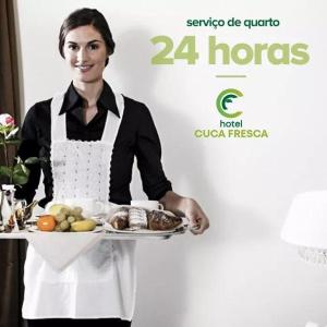 科蒂亞的住宿－HOTEL CUCA FRESCA - COTIA，把盘子上的食物托盘放在盘子里的妇女