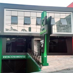 um edifício com um sinal verde em frente em HOTEL CUCA FRESCA - COTIA em Cotia