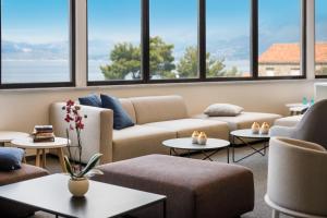 a living room with couches and tables and windows at Remisens Hotel Albatros-All inclusive in Cavtat
