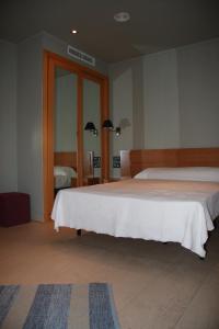 1 dormitorio con 2 camas y espejo en Hostal Playa Mazagon (El Remo), en Mazagón