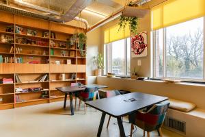 two tables and chairs in a room with bookshelves at ClinkNOORD Hostel in Amsterdam
