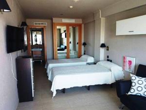 Habitación de hotel con 3 camas y TV de pantalla plana. en Hostal Playa Mazagon (El Remo), en Mazagón