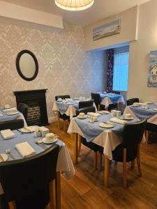 a dining room with blue tables and chairs and a fireplace at Hermosa Guest House in Scarborough