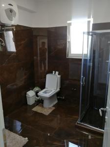 een badkamer met een toilet en een glazen douche bij Vila Emma in Durrës