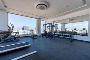 einen Fitnessraum mit Laufbändern und Maschinen in einem Zimmer mit Fenstern in der Unterkunft Brickell Apart Hotel in Santo Domingo