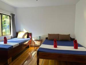 瓜隆島的住宿－快樂大像簡易別墅酒店，宿舍间内的两张床,配有红色枕头