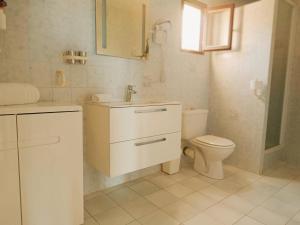 a white bathroom with a toilet and a sink at Residence Maïna in Cargèse