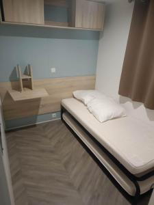 a small bed in a small room with white sheets at Mobilhome La Carabasse Vias Plage in Vias