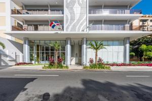 a building with palm trees in front of a street at Brickell Apart Hotel in Santo Domingo