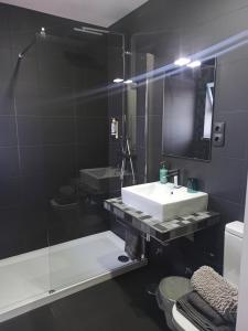 a bathroom with a sink and a glass shower at SUPERTUBOS HOUSE Peniche in Peniche