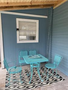 une table bleue et des chaises sur une terrasse couverte avec une table dans l'établissement The Painted Lady, a spacious renovated 4BR Victorian, à Saint Augustine