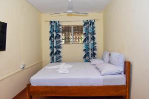 Schlafzimmer mit einem Bett mit weißer Bettwäsche und einem Fenster in der Unterkunft Double room in a villa in Diani Beach