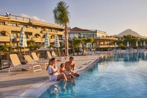 a family sitting in the pool at a resort at Grand Palladium Sicilia Resort & Spa in Campofelice di Roccella