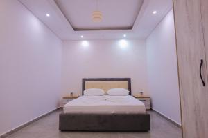 Un dormitorio con una cama en una habitación blanca. en J&M Luxury Apartments Saranda 2, en Sarandë