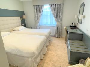 a hotel room with two beds and a desk at Centennial Hotel in Cambridge