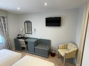 a bedroom with a desk and a bed and a tv at Centennial Hotel in Cambridge