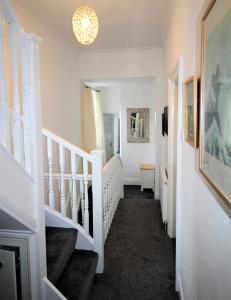 einen Flur mit weißen Treppen und einem Kronleuchter in der Unterkunft Newcastle - Heaton - Great Customer Feedback - 5 Large Bedrooms - Period Property - Refurbished Throughout in Newcastle upon Tyne