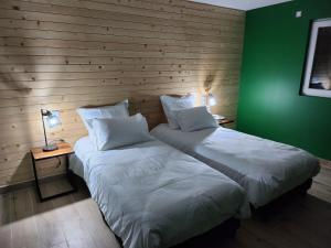 two beds in a room with a green wall at Chambres Jura Sud in Charchilla