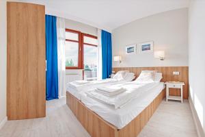 a bedroom with a large bed with blue curtains at Apartamenty Sun & Snow Neptun Park in Gdańsk