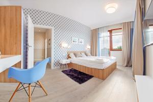 a bedroom with a bed and a blue chair at Apartamenty Sun & Snow Neptun Park in Gdańsk