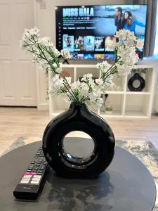 a black vase with flowers in it next to a remote control at Stylish Cosy Studio Apartment in Kent