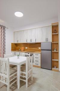cocina con mesa blanca y armarios blancos en J&M Luxury Apartments Saranda 2, en Sarandë